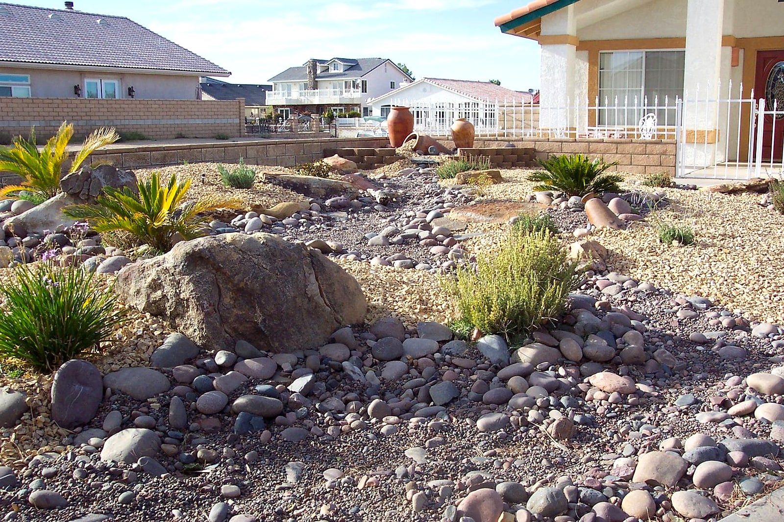 Front yard rockscape with a large boulder, agaves and river cobble