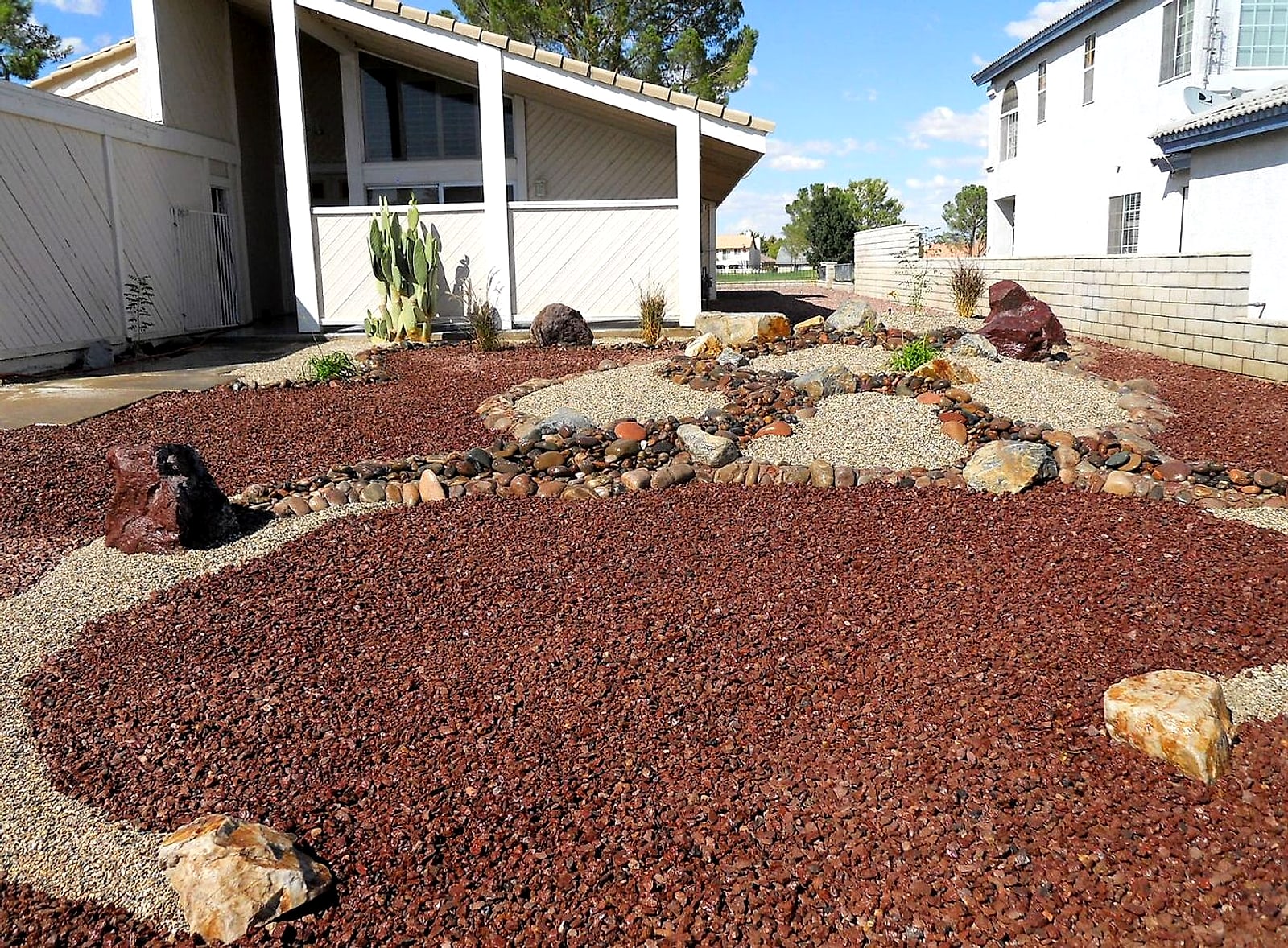 Front yard finished in red lava rock with gravel islands and boulders