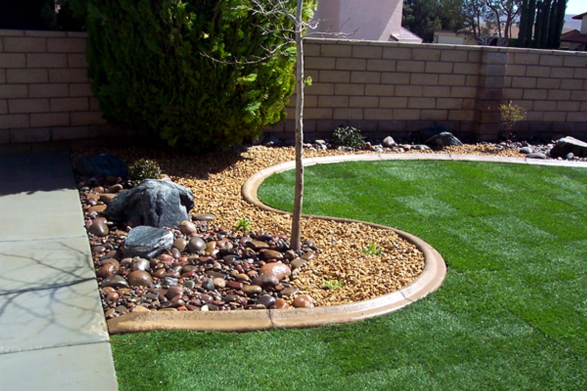 Curved concrete curbing around a lawn and rock bed
