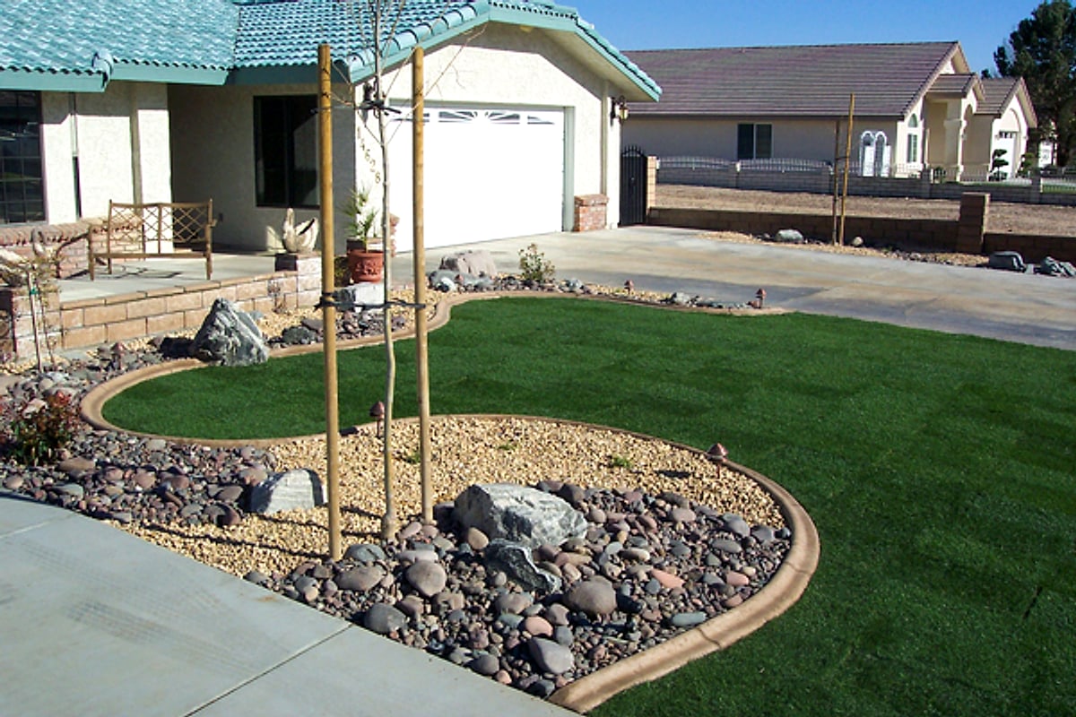 Front lawn with curbing, a rock bed and young trees