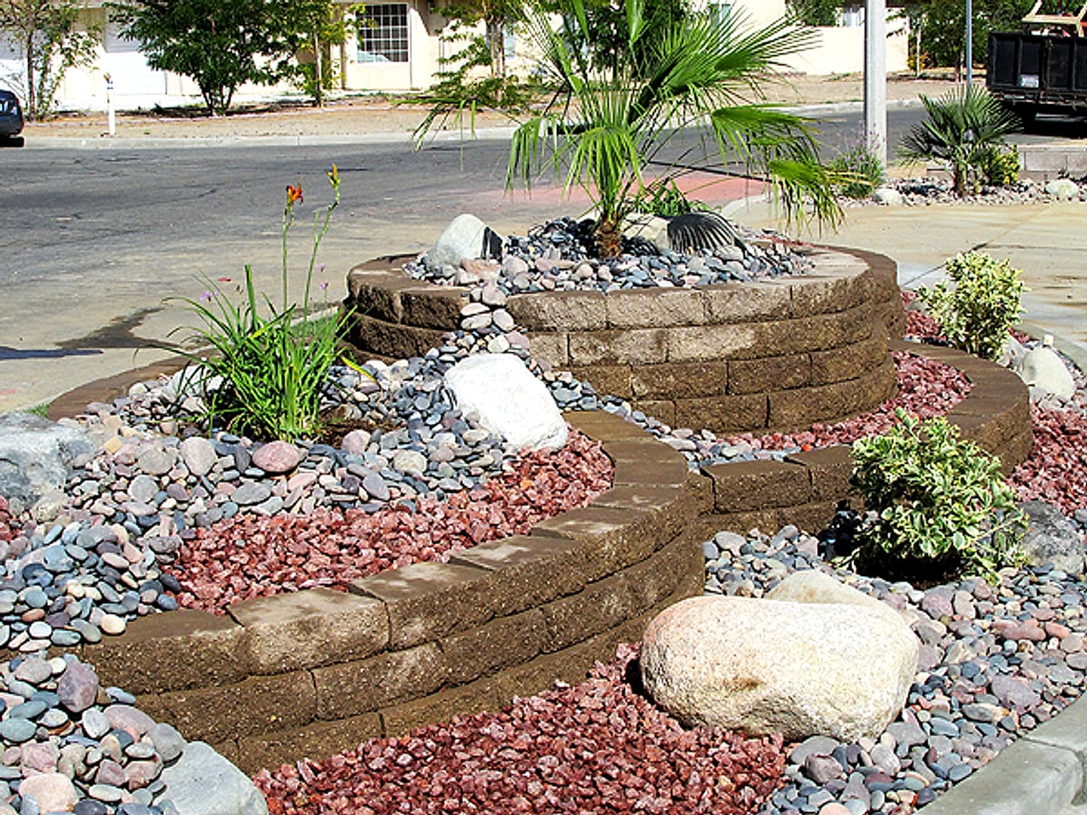 Tiered block planters with lava rock, boulders and a palm